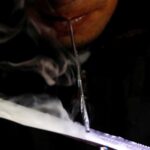A drug user inhales "Shabu", or methamphetamine, at a drug den in Manila
