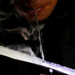 A drug user inhales "Shabu", or methamphetamine, at a drug den in Manila
