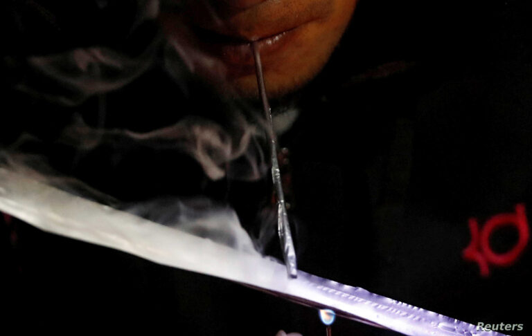 A drug user inhales "Shabu", or methamphetamine, at a drug den in Manila