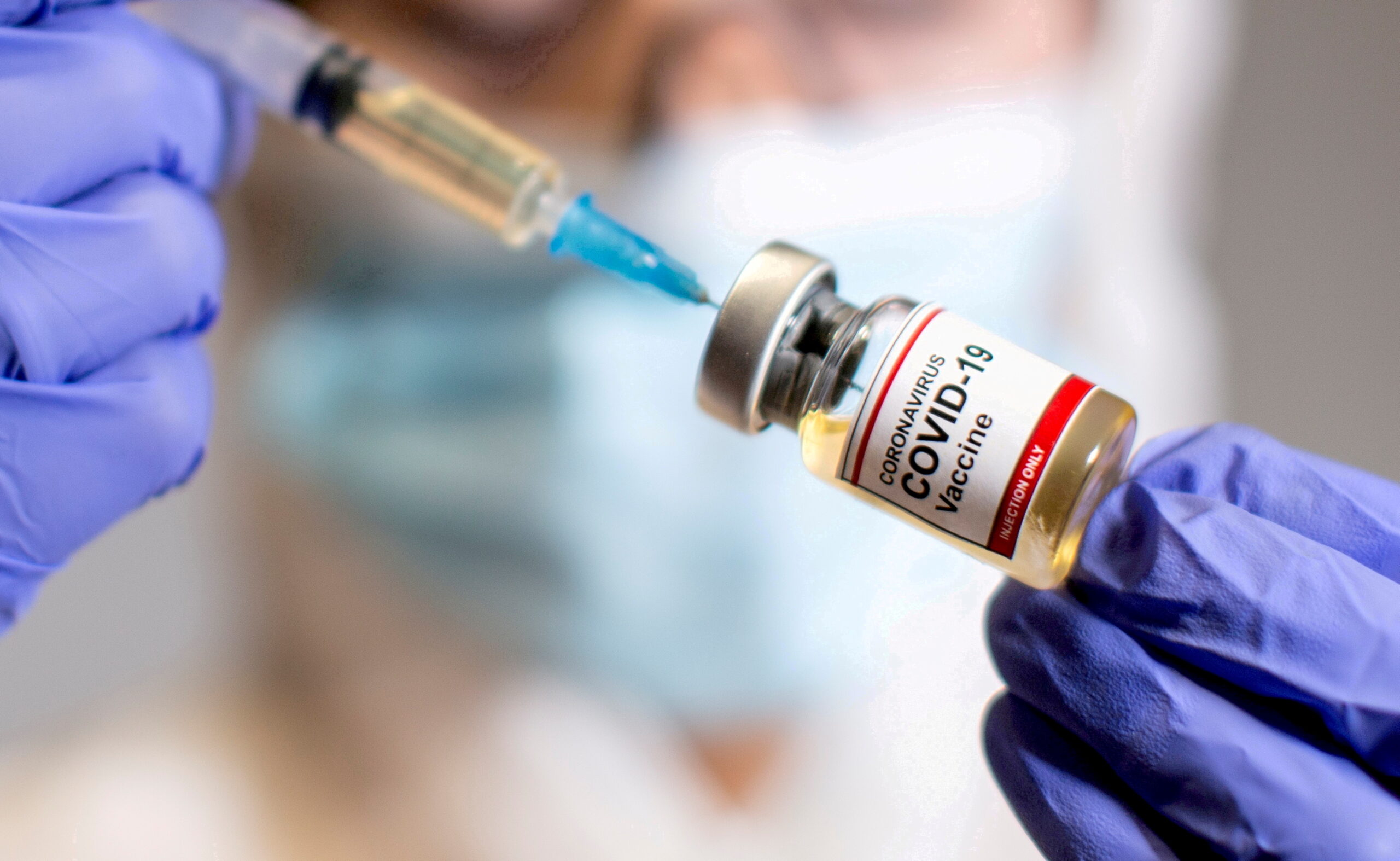 FILE PHOTO: FILE PHOTO: A woman holds a medical syringe and a small bottle labelled "Coronavirus COVID-19 Vaccine