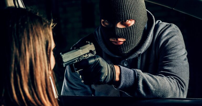 A Masked Robber With A Gun Threatens A Woman In A Car. Robbery.